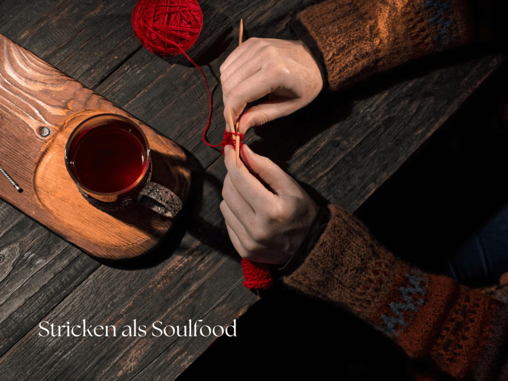 Hände beim Stricken mit roter Wolle und einer Tasse Tee als ruhiger Moment für Stricken als Soulfood