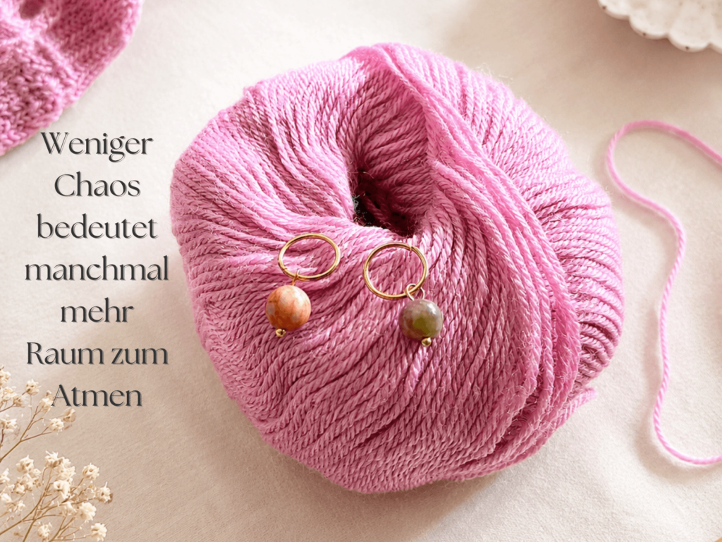 Rosa Garnknäuel mit Maschenmarkierern und ruhiger natürlicher Dekoration für bewusstes Handarbeiten